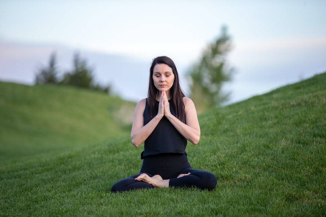 a women meditating on grass